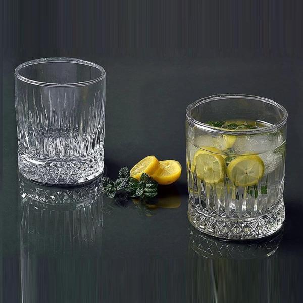 Trei pahare tip tumbler cu dungi verticale pline cu cocktail de culoarea chihlimbarului si gheata, asezate pe un fundal intunecat si estetic de bar.