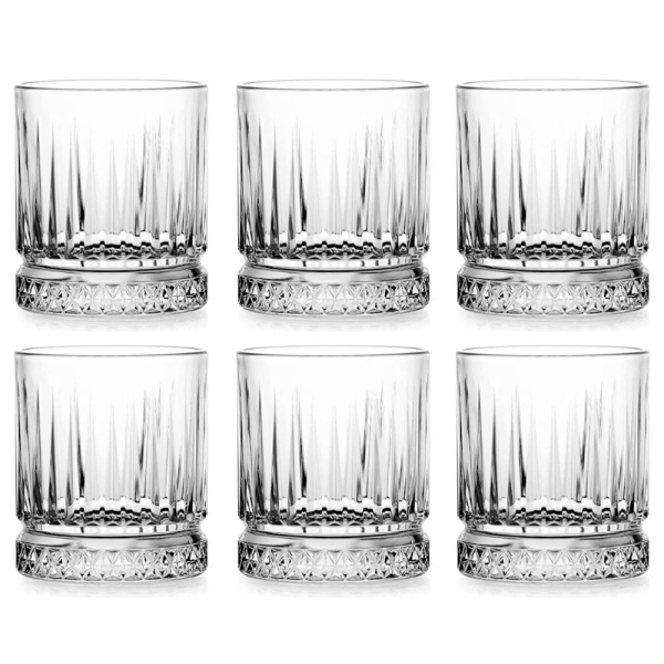Set de sase pahare din sticla cu dungi verticale MADGENIX, asezate in linie pe o masa eleganta din lemn, umplute cu whisky si cuburi de gheata.