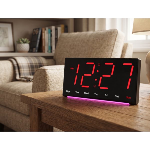 Ceas digital LED de noptiera cu lumina rosie amplasat pe o comoda din lemn intr-un dormitor calduros.