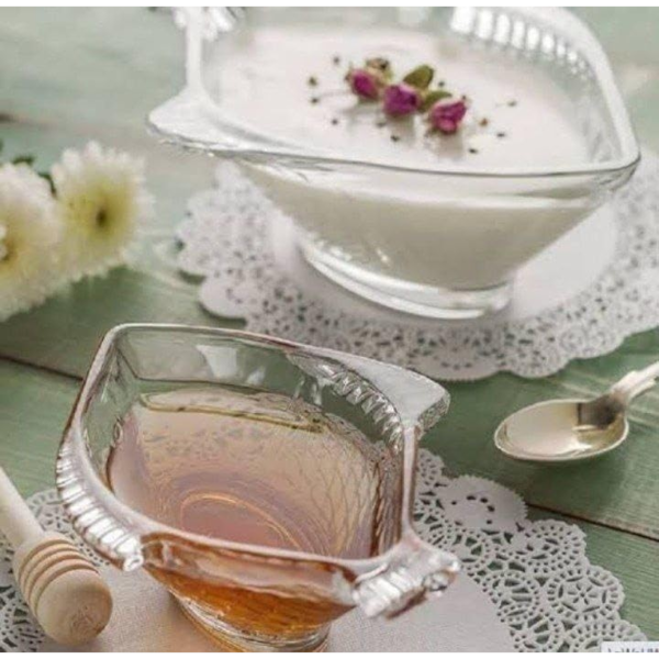 Două boluri în formă de pește umplute cu crema de lapte și miere așezate pe șervețele dantelate.